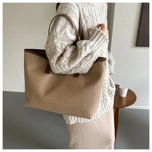 Gros plan détaillé sur la texture tressée et le similicuir de ce grand sac cabas beige