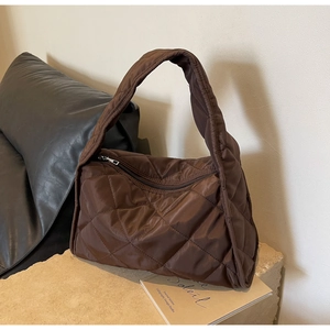 Détail d'un sac bandoulière matelassé café noir avec texture lisse et zip argenté