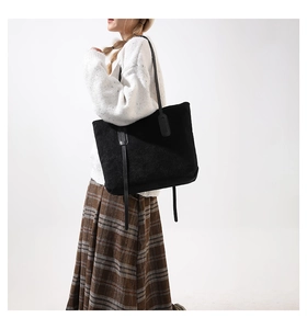 Detail of a large black corduroy tote bag with long straps for a minimalist casual look
