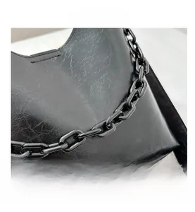 Detail of black pleated tote bag with oily texture finish and chunky chain handle