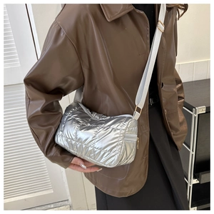 Détail d'un sac matelassé argenté avec finition métallisée et bandoulière réglable