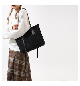 Detail shot of black corduroy tote bag showing ribbed texture and leather shoulder straps