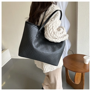 Détail du sac cabas en cuir noir tressé avec de fines bandoulières élégantes