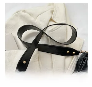 Detail of black faux leather shoulder strap with golden rivets and metal chain links