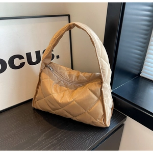 Détail de la texture matelassée kaki et de la finition brillante sur le sac à main chic