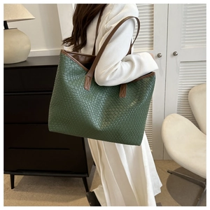 Détail d'un grand sac cabas en cuir tressé vert foncé avec des anses marron