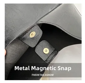 Detail of the high-quality magnetic snap closure on a black soft leather shoulder bag