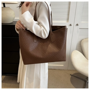 Dettaglio di una grande borsa tote intrecciata marrone con motivo a traliccio e tracolle