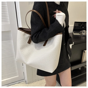 Gros plan du grand sac cabas tissé blanc avec anses marron dans un décor de bureau moderne