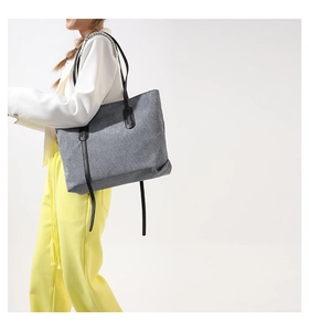 Detail of grey corduroy tote bag with long straps shown on shoulder for daily use