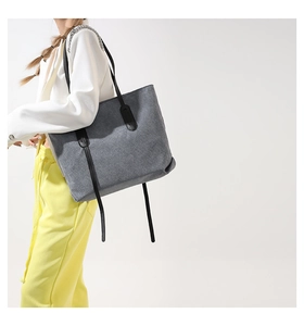 Detailed texture of gray corduroy tote bag with black shoulder straps and long straps