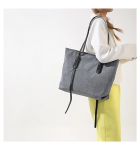 Detail of gray corduroy tote bag with vertical texture and black leather straps