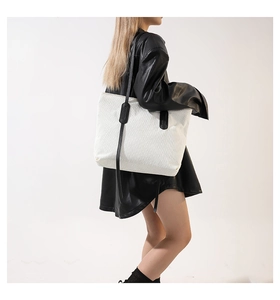 Detailed texture of white corduroy tote bag with black leather shoulder straps
