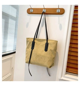 Detail view of large pale yellow corduroy tote bag hanging on a wooden wall hook