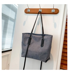 Detail view of grey corduroy tote bag showing vertical rib texture and black leather handles