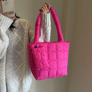 Pink quilted tote bag with matching coin pouch shown in a casual shoulder carry style