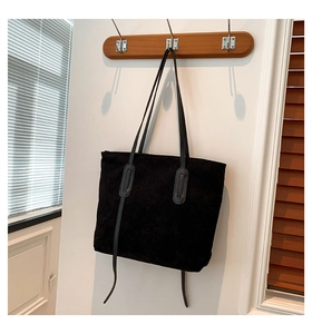 Detail of black corduroy tote bag showing fine ribbed texture and leather accents