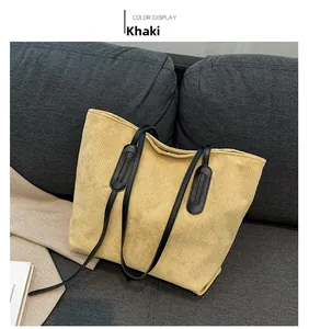 Detail of khaki corduroy tote bag showing ribbed texture and black leather shoulder straps