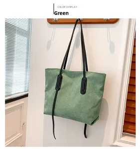Detail of green corduroy tote bag with black leather handles and vertical ribbed texture