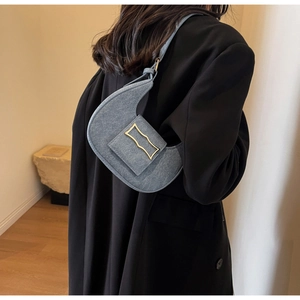 Detailed view of the denim texture and golden clasp on a crescent-shaped underarm bag