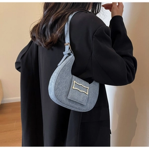 Detail of light blue crescent bag with gold buckle on a model in a black suit