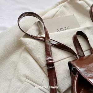 Detail of adjustable metal buckle on retro dark brown leather strap with glossy finish