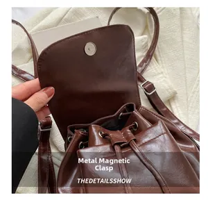 Detail of brown glossy leather backpack showing the magnetic snap and drawstring closure