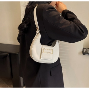 Detail of white half-moon shoulder bag with gold geometric buckle on a black suit