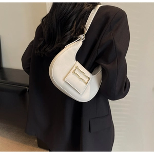 Detail showing creamy white crescent armpit bag with golden geometric metal buckle