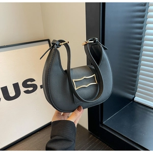 Detailed shot of a black crescent shoulder bag featuring a golden rectangular metal buckle