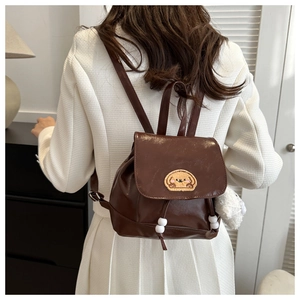 Detail of dark brown mini leather backpack with cartoon puppy embroidery and plush charm