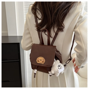 Detail view of mini brown faux leather backpack with dog embroidery and plush bear charm