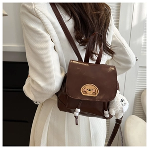 Detail of a mini brown backpack with puppy embroidery and a white plush sheep charm