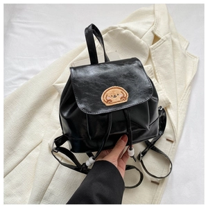 Detail of black PU leather backpack featuring a yellow puppy embroidery and drawstring