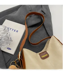 Detail of cream and brown patchwork bucket bag with adjustable wide strap and plush ball charm