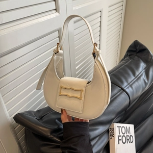 White minimalist crescent shoulder bag with geometric gold clasp in a stylish hand-held pose