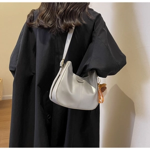 Detail of soft leather crescent bag featuring fashion label and brown plush charm accessory