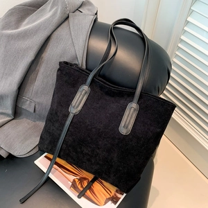Chic black corduroy tote bag with leather handles in a stylish minimalist setting