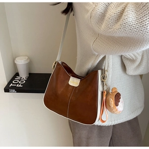 Brown and white faux leather tote bag detail with fashion label and plush bear charm