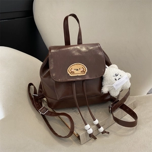 Deep brown glossy faux leather backpack with dog embroidery and plush bear charm
