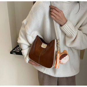 Detail of soft leather tote with gold metal tag and a cute plush bear charm accessory
