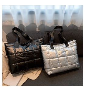 Detail of silver and black quilted tote bags with metallic finish on a sofa