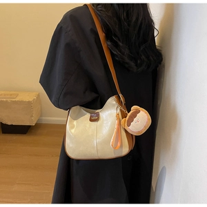 Detail of soft beige tote bag with brown leather trim and cute plush charm on shoulder