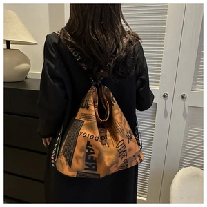 Detail of orange tote bag with vintage newspaper print and colorful LOVE guitar strap