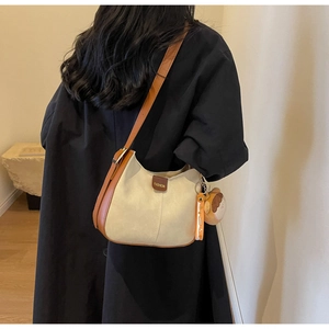 Detail of soft cream tote bag with brown leather strap and cute bear keychain accessory