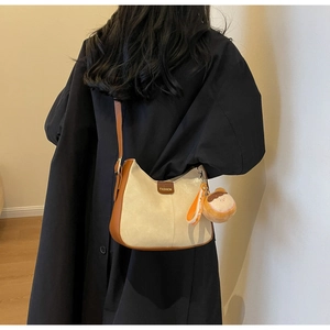 Detail of soft beige tote bag with brown leather trim and cute bread-shaped charm
