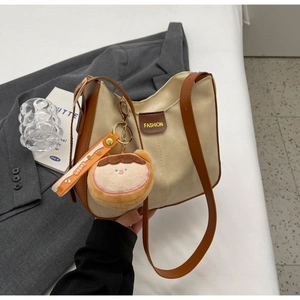 Detail of vintage beige fabric shoulder bag with brown leather trim and plush bread charm