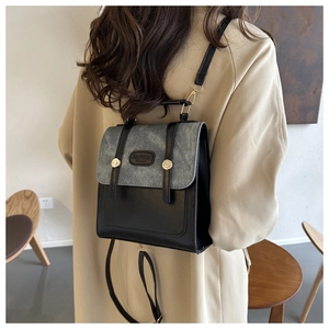 Vue détaillée d'un sac à dos rétro en cuir noir et denim gris porté sur un trench-coat
