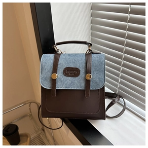 Détail du sac à dos vintage en cuir marron avec rabat en patchwork bleu et boucle dorée