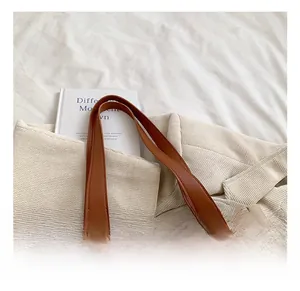 Detail showing the brown leather handles and dual-tone patchwork on the beige tote bag